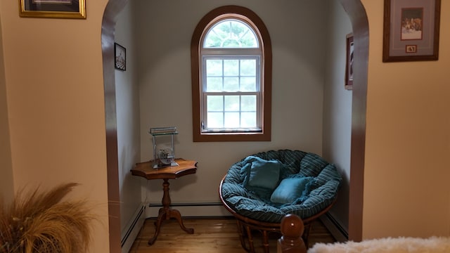 55 Pember Rd, Levant, ME 04456 - living area featuring arched walkways, wood finished floors, a baseboard heating unit, and baseboards