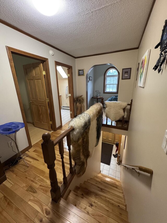 55 Pember Rd, Levant, ME 04456 - staircase featuring hardwood / wood-style floors, ornamental molding, baseboard heating, arched walkways, and a textured ceiling