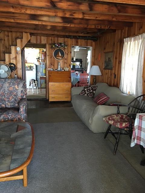 233 Webhannet Dr, Wells, ME 04090 - living area featuring wooden walls, gas water heater, beam ceiling, and dark carpet