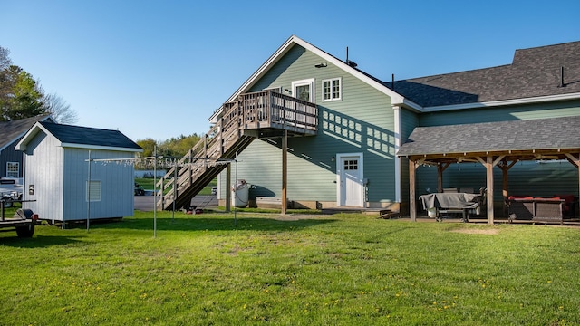 815 Grant Rd, Corinth, ME 04427 - rear view of house with a lawn, an outdoor living space, a shingled roof, a deck, and a storage unit