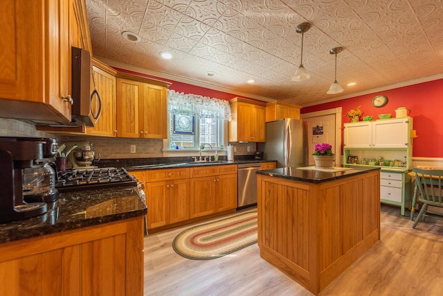 815 Grant Rd, Corinth, ME 04427 - kitchen featuring appliances with stainless steel finishes, light wood-style flooring, a center island, ornamental molding, and backsplash