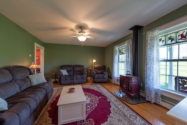 815 Grant Rd, Corinth, ME 04427 - living room featuring a wood stove, wood finished floors, ceiling fan, and a baseboard radiator