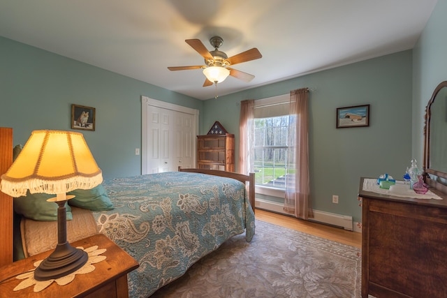 815 Grant Rd, Corinth, ME 04427 - bedroom featuring wood finished floors, a baseboard heating unit, a closet, and a ceiling fan