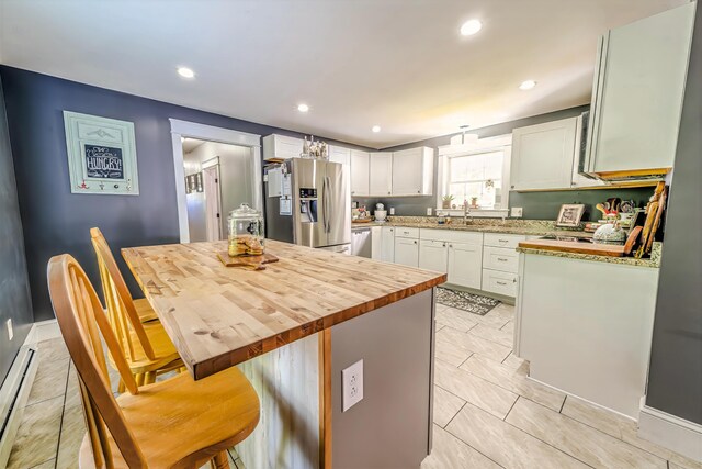 304 Main Rd N, Hampden, ME 04444 - kitchen with stainless steel fridge, butcher block counters, a baseboard heating unit, white cabinetry, and a kitchen bar