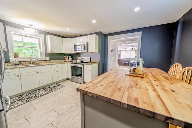304 Main Rd N, Hampden, ME 04444 - kitchen with appliances with stainless steel finishes, a sink, butcher block countertops, a chandelier, and white cabinets