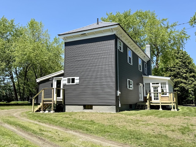 88 Union St, Calais, ME 04619 - view of property exterior featuring a deck, a lawn, and a chimney