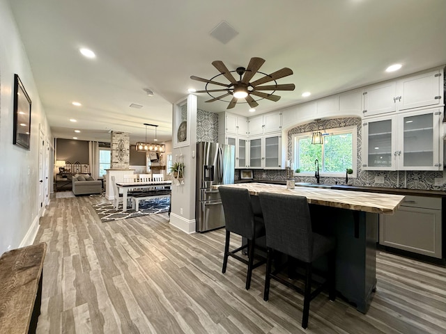 88 Union St, Calais, ME 04619 - kitchen featuring butcher block countertops, stainless steel fridge with ice dispenser, decorative backsplash, baseboards, and recessed lighting