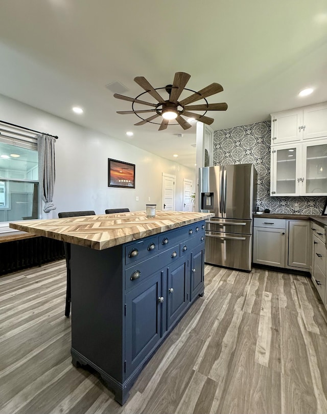 88 Union St, Calais, ME 04619 - kitchen with stainless steel fridge with ice dispenser, butcher block counters, light wood-type flooring, blue cabinets, and recessed lighting