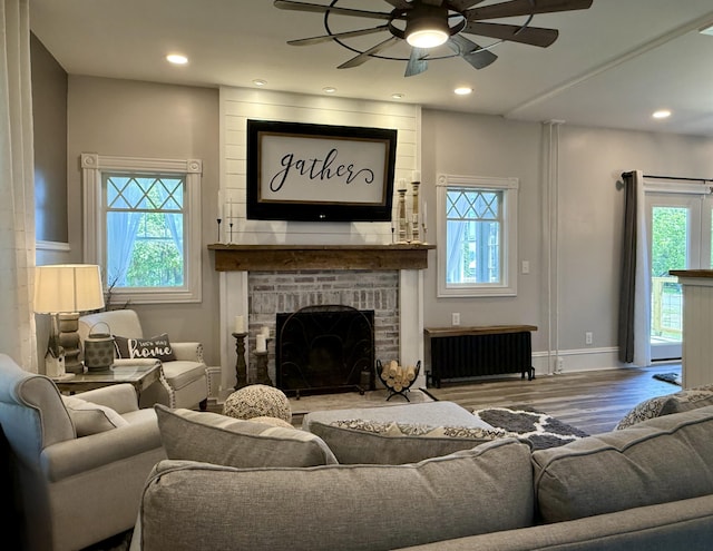 88 Union St, Calais, ME 04619 - living area featuring a ceiling fan, radiator heating unit, wood finished floors, a brick fireplace, and recessed lighting