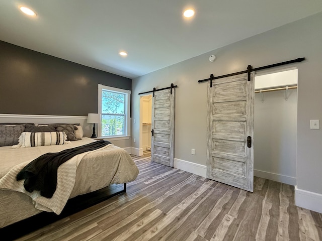 88 Union St, Calais, ME 04619 - bedroom with a barn door, wood finished floors, baseboards, and recessed lighting