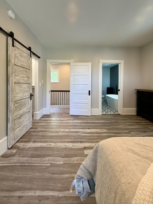 88 Union St, Calais, ME 04619 - bedroom featuring a barn door, wood finished floors, baseboards, and connected bathroom