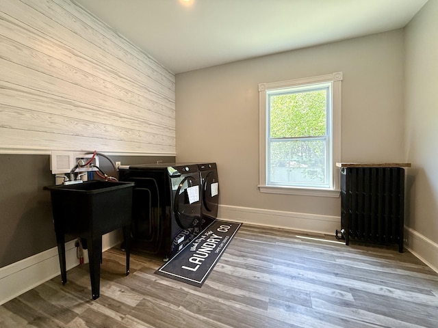 88 Union St, Calais, ME 04619 - laundry area with washing machine and clothes dryer, wood walls, wood finished floors, radiator, and baseboards