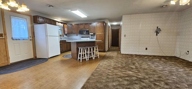20 Oosoola St, Norridgewock, ME 04957 - kitchen featuring freestanding refrigerator, black microwave, a chandelier, a breakfast bar, and a kitchen island