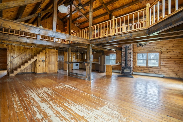 526 Range Rd, Dover-Foxcroft, ME 04426 - unfurnished living room featuring high vaulted ceiling, a wood stove, hardwood / wood-style floors, wood walls, and baseboard heating