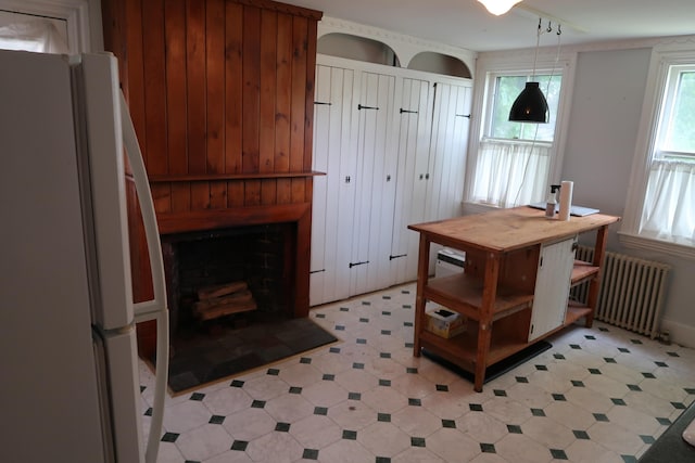7 Elm St, Augusta, ME 04330 - kitchen featuring freestanding refrigerator, radiator, a fireplace, decorative light fixtures, and light flooring