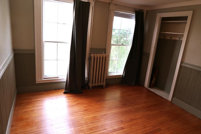7 Elm St, Augusta, ME 04330 - unfurnished bedroom featuring radiator heating unit, wainscoting, light wood finished floors, and wood walls