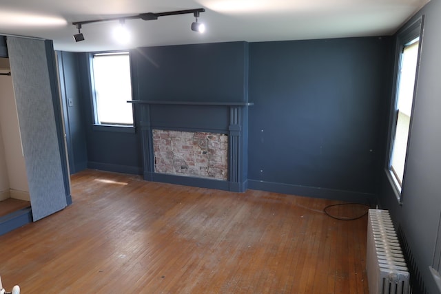 7 Elm St, Augusta, ME 04330 - unfurnished living room with radiator, hardwood / wood-style floors, a fireplace, track lighting, and baseboards