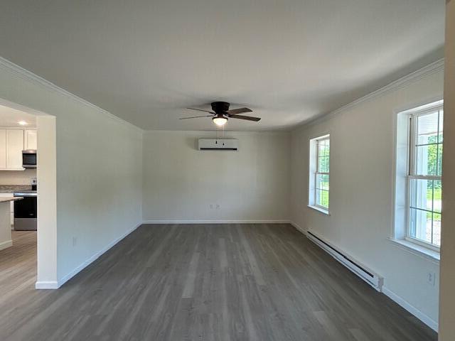 144 Curtis St, Pittsfield, ME 04967 - empty room with baseboard heating, crown molding, dark wood-style floors, ceiling fan, and baseboards
