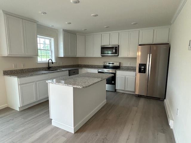 144 Curtis St, Pittsfield, ME 04967 - kitchen with stainless steel appliances, a sink, light wood-style flooring, baseboards, and a center island