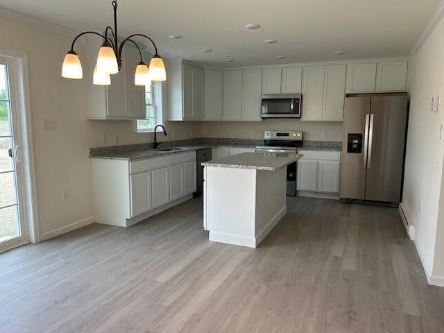 144 Curtis St, Pittsfield, ME 04967 - kitchen with stainless steel appliances, a sink, light wood finished floors, crown molding, and a kitchen island