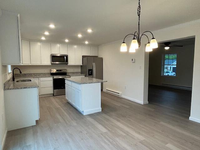 144 Curtis St, Pittsfield, ME 04967 - kitchen featuring stainless steel appliances, baseboard heating, a sink, crown molding, and white cabinets