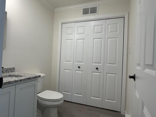 144 Curtis St, Pittsfield, ME 04967 - bathroom with a closet, ornamental molding, vanity, wood finished floors, and toilet