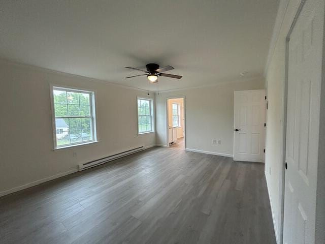 144 Curtis St, Pittsfield, ME 04967 - spare room with baseboard heating, ceiling fan, dark wood-type flooring, baseboards, and crown molding