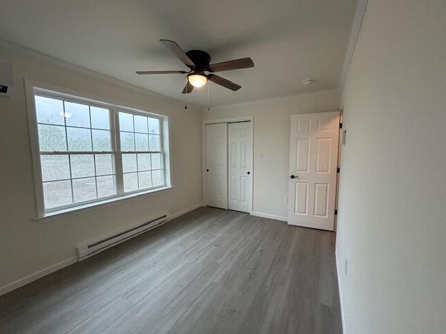 144 Curtis St, Pittsfield, ME 04967 - unfurnished bedroom featuring a baseboard heating unit, wood finished floors, a closet, baseboards, and a ceiling fan