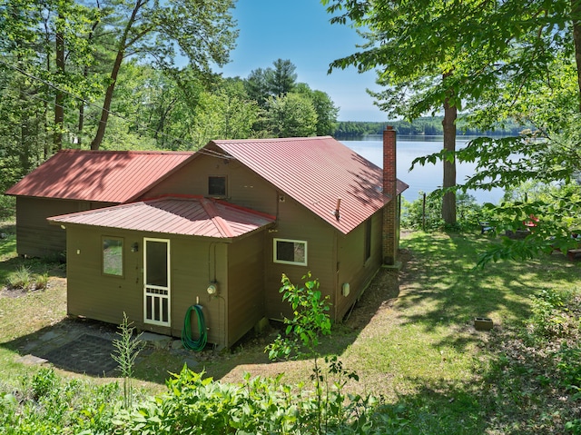 66 Myron Hall Rd, Raymond, ME 04071 - view of home's exterior with a water view, a chimney, a yard, and metal roof
