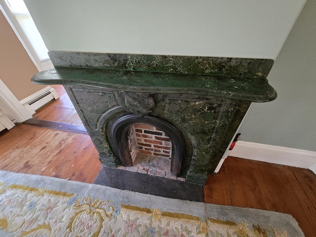 25 Jarvis Gore Dr, Eddington, ME 04428 - detailed view of baseboards, wood finished floors, a baseboard heating unit, and a fireplace with flush hearth