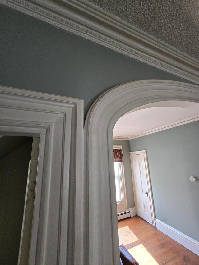 25 Jarvis Gore Dr, Eddington, ME 04428 - hall with arched walkways, crown molding, baseboard heating, light wood finished floors, and baseboards