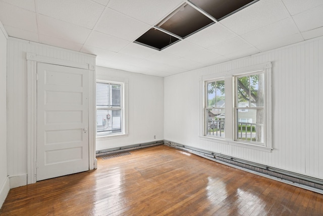 9 Maple St, Jay, ME 04239 - empty room with hardwood / wood-style flooring, a drop ceiling, and baseboard heating