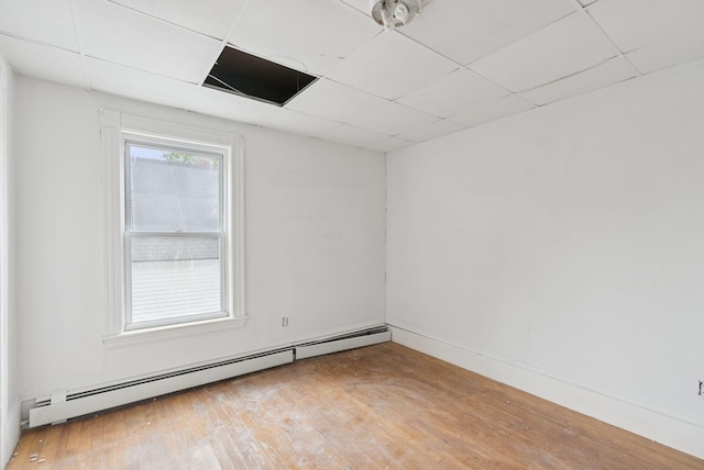 9 Maple St, Jay, ME 04239 - empty room with a baseboard radiator, wood finished floors, and a paneled ceiling