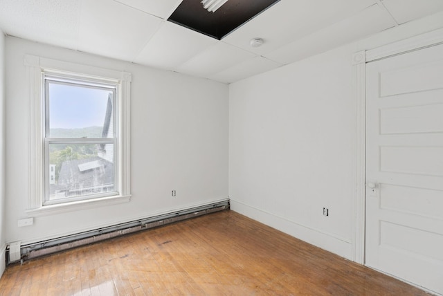 9 Maple St, Jay, ME 04239 - empty room with a baseboard heating unit, a smoke detector, and wood finished floors