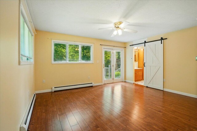 14 Goshen Ln, New Gloucester, ME 04260 - spare room with a baseboard heating unit, baseboard heating, ceiling fan, a barn door, and hardwood / wood-style flooring