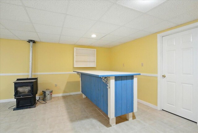 14 Goshen Ln, New Gloucester, ME 04260 - kitchen featuring a wood stove, baseboards, a drop ceiling, light countertops, and a kitchen breakfast bar