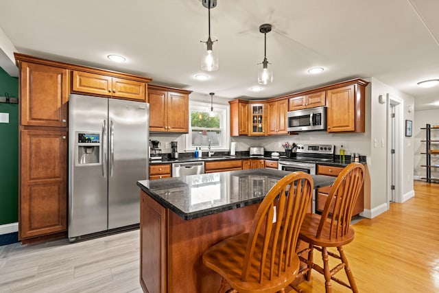 534 Summit St, Portland, ME 04103 - kitchen featuring stainless steel appliances, brown cabinets, a kitchen breakfast bar, light wood-style floors, and decorative light fixtures