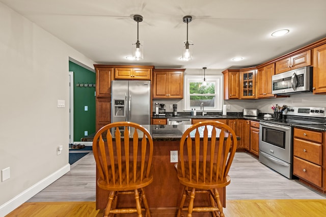 534 Summit St, Portland, ME 04103 - kitchen with appliances with stainless steel finishes, brown cabinets, a center island, a breakfast bar area, and light wood-type flooring