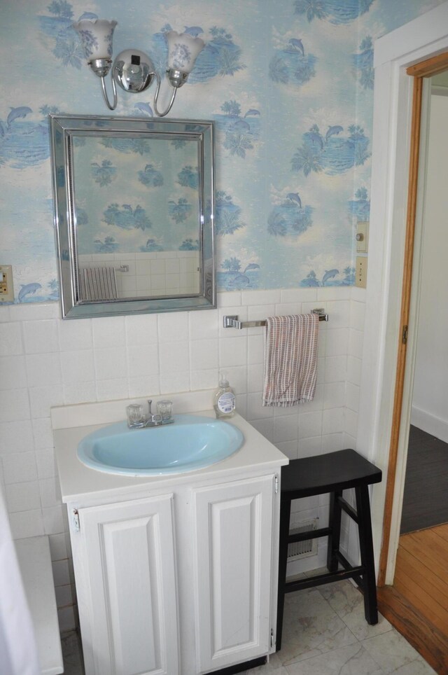 5 Charles St, Orono, ME 04473 - bathroom with wallpapered walls, tile walls, vanity, and a wainscoted wall