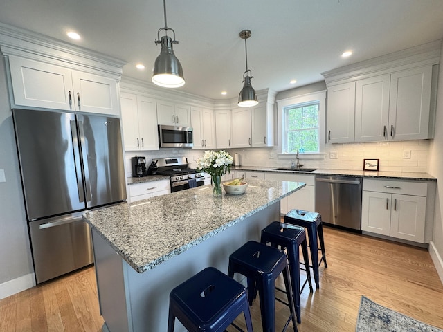3 Jennifer Ln Unit 1, Wells, ME 04090 - kitchen featuring appliances with stainless steel finishes, a sink, a kitchen breakfast bar, light wood finished floors, and light stone counters