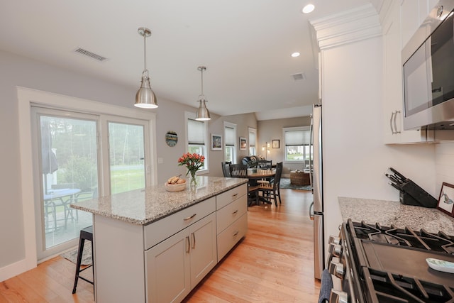 3 Jennifer Ln Unit 1, Wells, ME 04090 - kitchen featuring appliances with stainless steel finishes, light wood finished floors, a center island, white cabinets, and light stone counters