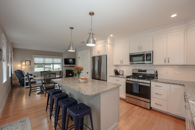 3 Jennifer Ln Unit 1, Wells, ME 04090 - kitchen featuring appliances with stainless steel finishes, white cabinets, decorative backsplash, a breakfast bar area, and a center island