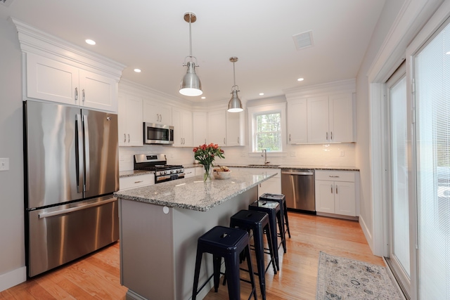 3 Jennifer Ln Unit 1, Wells, ME 04090 - kitchen featuring appliances with stainless steel finishes, white cabinets, a kitchen bar, backsplash, and light wood-type flooring