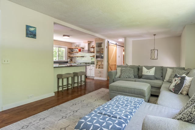 18 Brian Dr, Brewer, ME 04412 - living area featuring a barn door, dark wood-style flooring, baseboards, and a textured ceiling