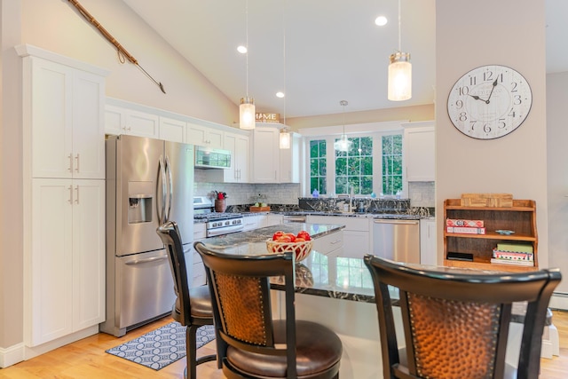 2 Neptune Rd, Old Orchard Beach, ME 04064 - kitchen featuring stainless steel appliances, decorative backsplash, a breakfast bar, light wood finished floors, and white cabinetry