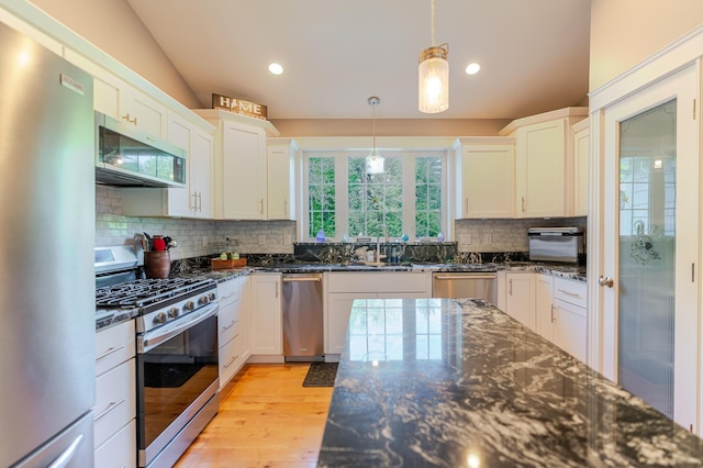 2 Neptune Rd, Old Orchard Beach, ME 04064 - kitchen with appliances with stainless steel finishes, a sink, backsplash, dark stone countertops, and hanging light fixtures