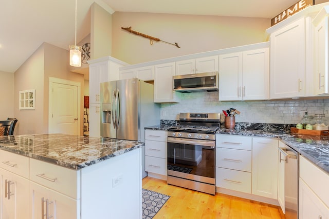 2 Neptune Rd, Old Orchard Beach, ME 04064 - kitchen with stainless steel appliances, tasteful backsplash, dark stone countertops, white cabinets, and light wood-type flooring