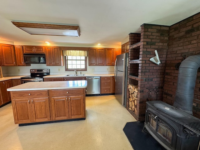 124 Swan Rd, Hermon, ME 04401 - kitchen with stainless steel appliances, a wood stove, a sink, light countertops, and a center island