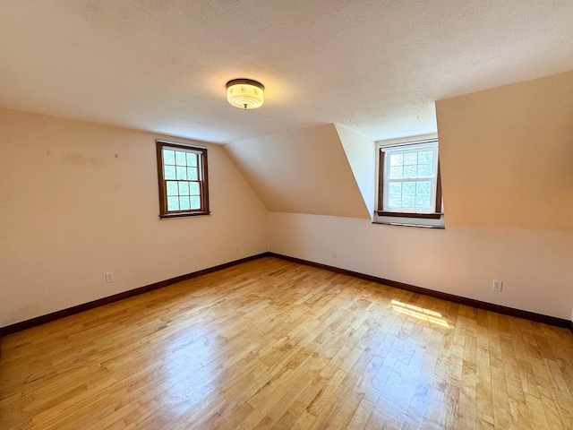 124 Swan Rd, Hermon, ME 04401 - additional living space with plenty of natural light, wood finished floors, vaulted ceiling, baseboards, and a textured ceiling