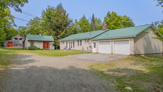 52A Judkins Rd, Harmony, ME 04942 - view of front of home featuring a chimney, a front yard, metal roof, asphalt driveway, and a garage